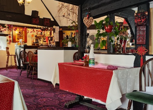 The dining room at Yumi Yumi with red linen tables and the bar behind